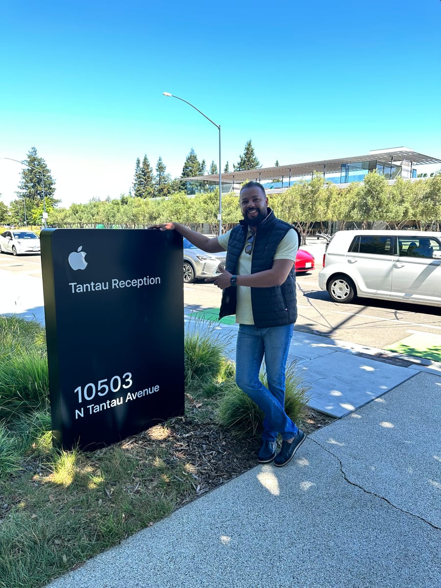 Gleidson Andrade ao lado do letreiro Tantau Reception do Apple Park, com o edifício da Apple ao fundo, em Cupertino