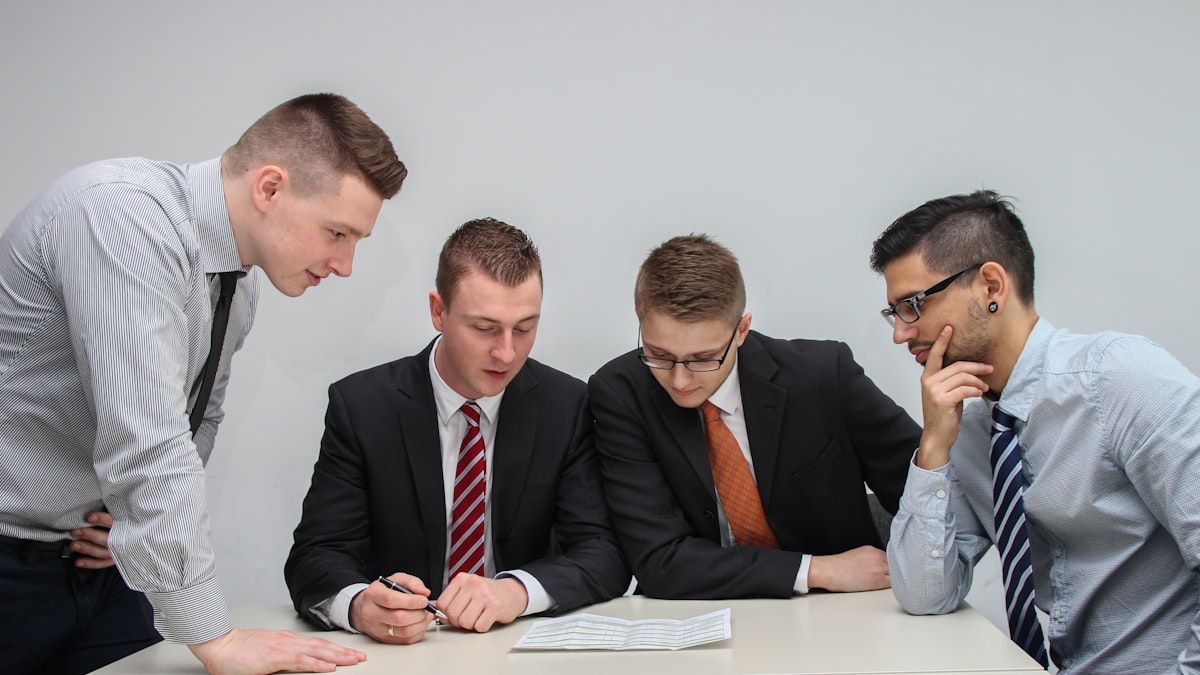 Grupo de profissionais analisando um documento sobre a mesa antes de fechar um contrato