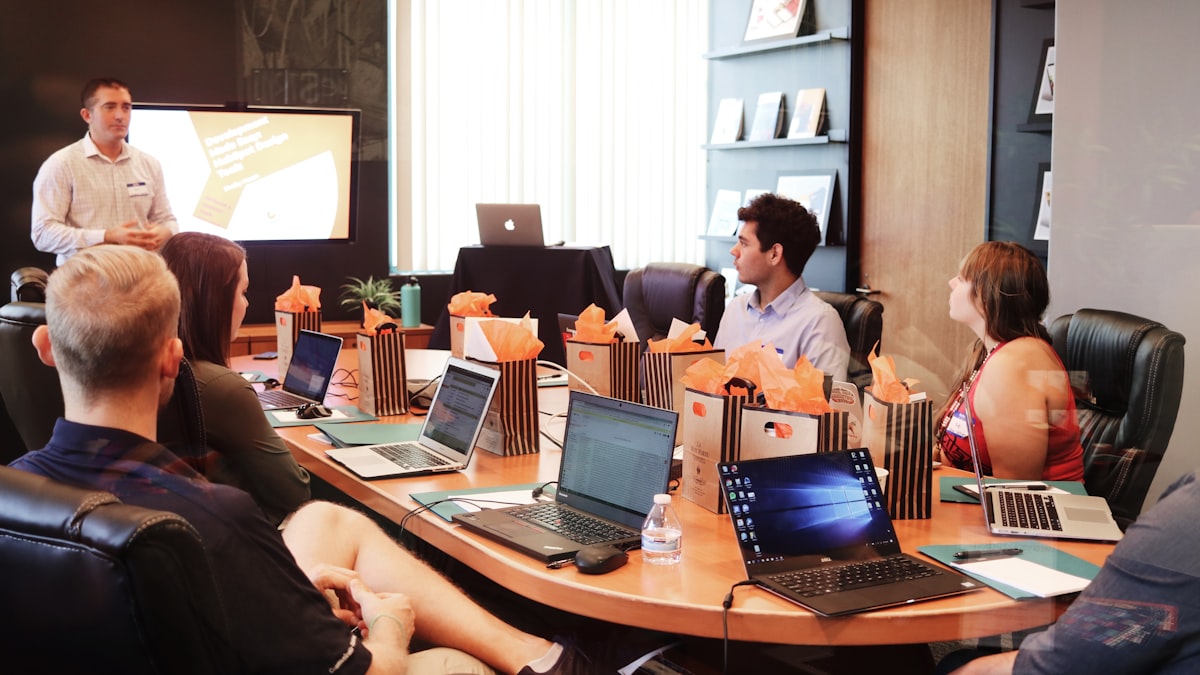 Equipe de uma pequena empresa reunida ao redor de laptops discutindo tecnologia